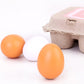 Toy egg set with orange and white eggs on surface and open carton lid