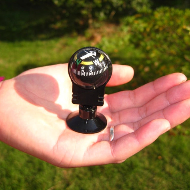 Black handheld-style navigation compass with compass dial and suction base held in hand