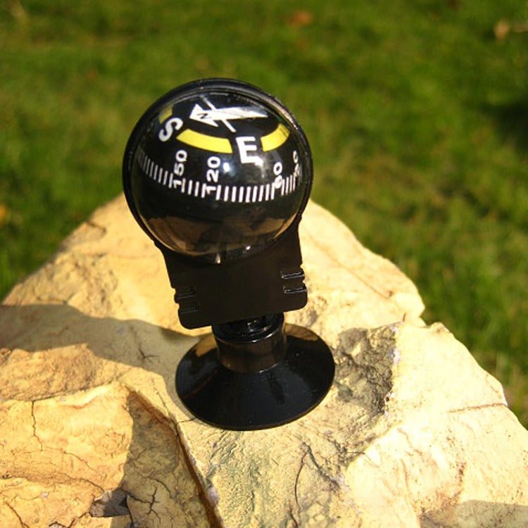 Black navigation compass with direction dial on round suction base outdoors