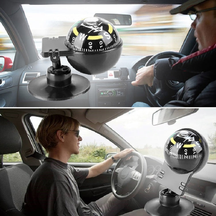Suction-mounted black navigation compass on car dashboard near steering wheel