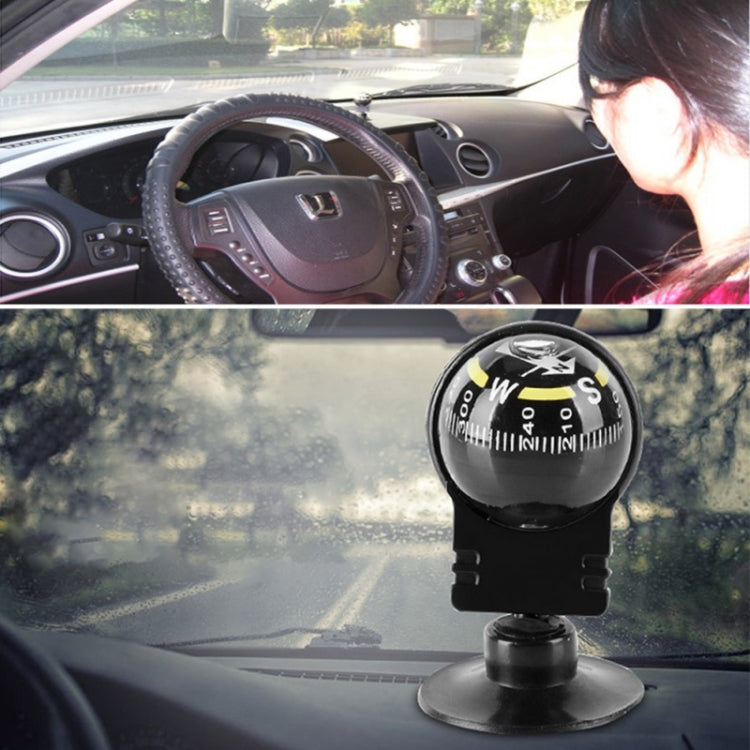 Black suction-mount navigation compass inside car windshield view with dial facing up