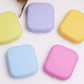 Mini square contact lens cases in light blue, lilac, yellow, and pink—closed