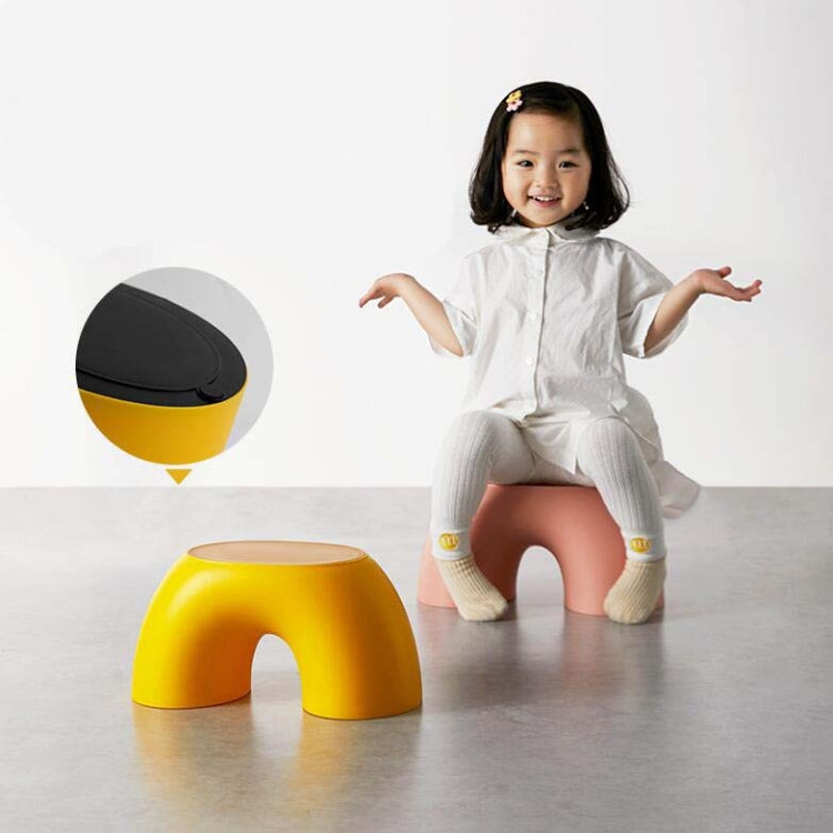 Yellow round kids stool with flat top and front cutout; includes black underside pad.