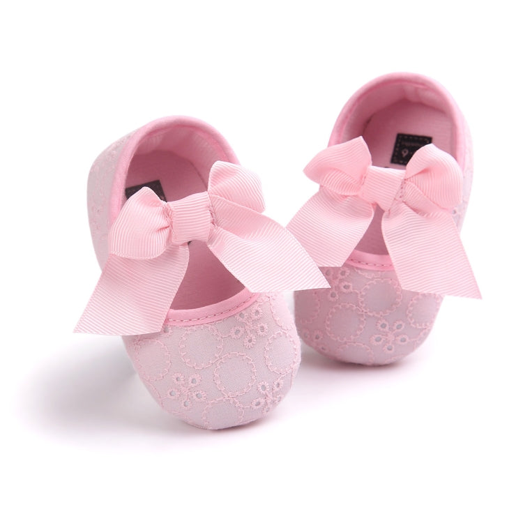 Toddler light pink slip-on shoes with large pink bow and textured eyelet upper
