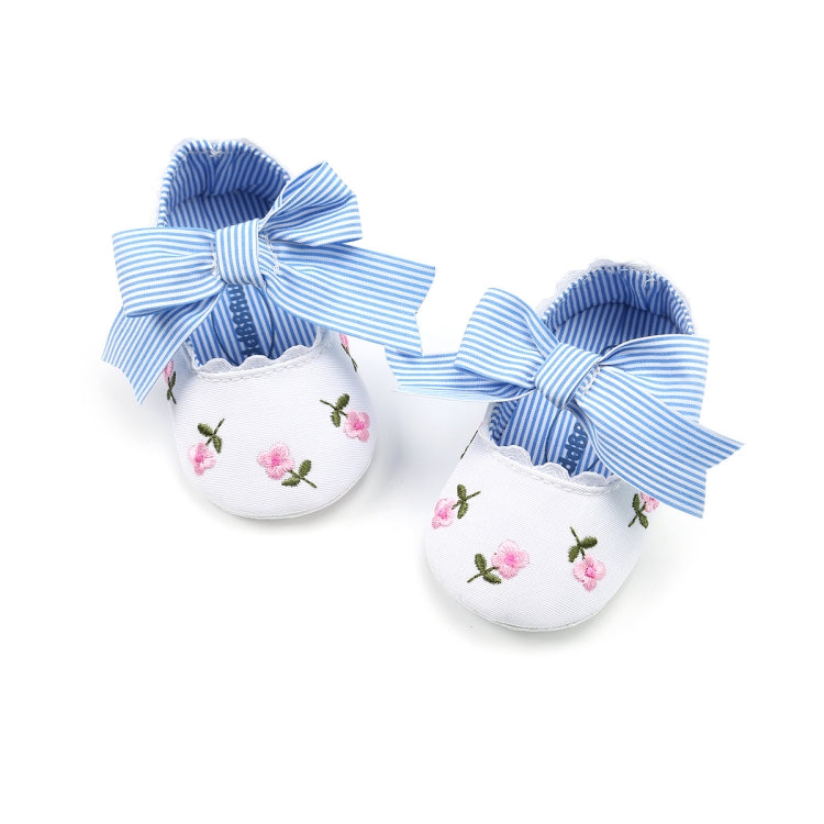 Pair of white toddler slip-on shoes with pink floral embroidery and blue striped bows