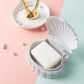 Gray seashell soap dish with flip lid holding a white bar of soap