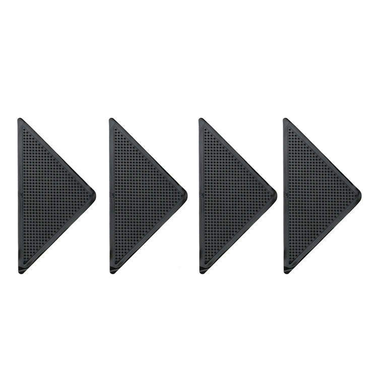 Set of four triangular black non-slip floor stickers with dot-texture grips.
