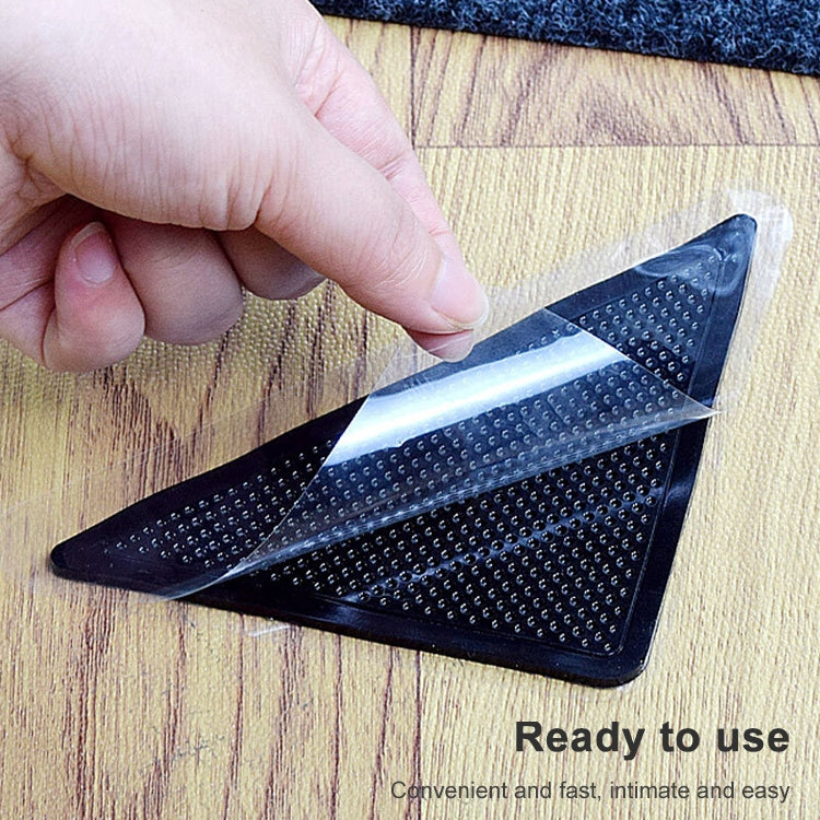 Hand applying black triangular non-slip bath mat sticker with clear backing film on wood.