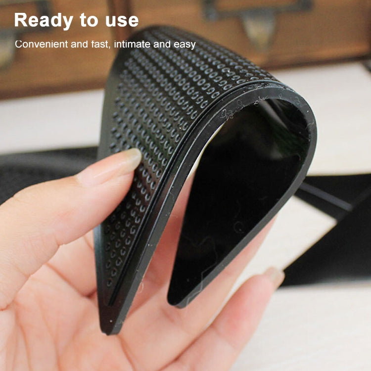 Black triangular non-slip mat sticker roll-up close-up showing textured underside grip.