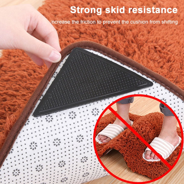 Triangular black non-slip sticker pressed onto carpet to help prevent sliding.