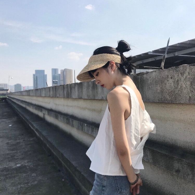 Woven straw visor hat with wide brim on model, featuring dark headband and tie.