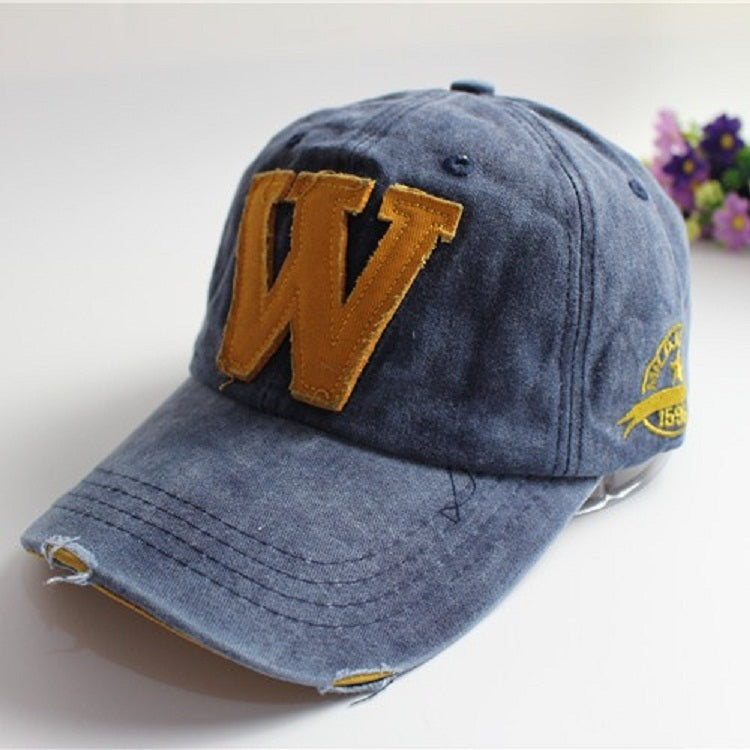 Denim blue canvas baseball cap with orange 'W' applique and yellow side badge