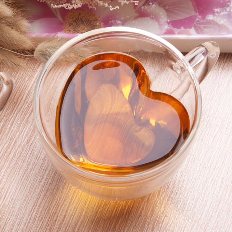 Heart-shaped double-wall tea cup with amber drink inside, transparent glass