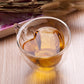 Heart-shaped double-wall glass mug holding amber tea with visible heart silhouette