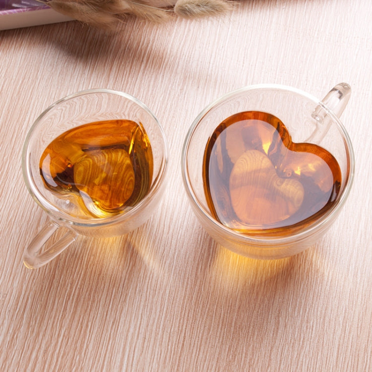 Set of two heart-shaped double-wall glass mugs with amber tea, each with handle