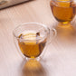 Heart-shaped double-wall glass mug with amber tea and side handle, transparent cup