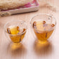 Two heart-shaped double-wall glass mugs filled with amber tea, clear glass handles