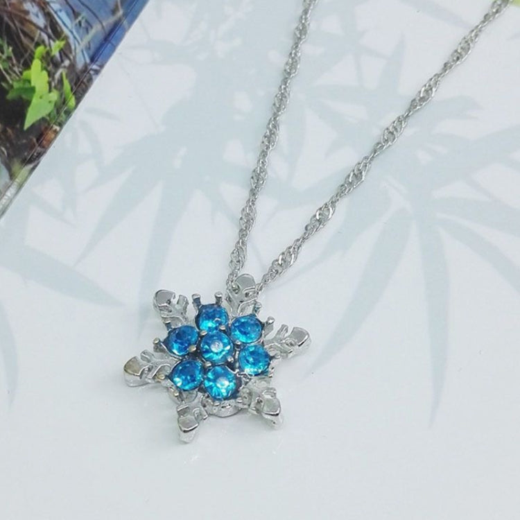 Silver-tone necklace with blue crystal snowflake flower pendant, close-up