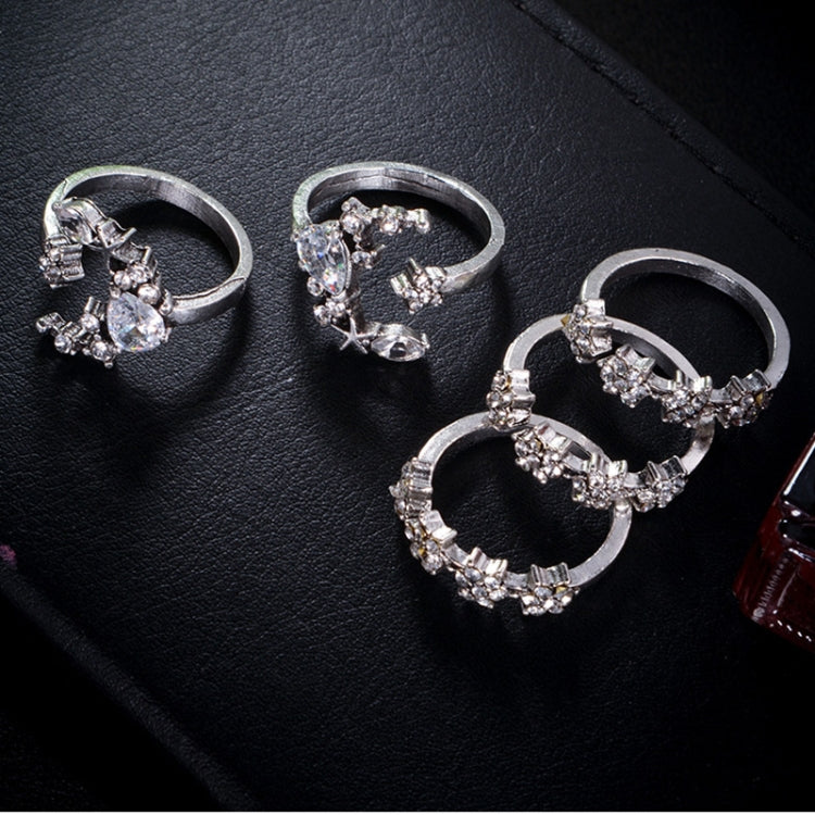 Five adjustable silver-tone star-and-moon rings with clear stones on dark surface