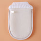 Natural loofah bath glove back view with ribbed white cuff and small fabric label patch
