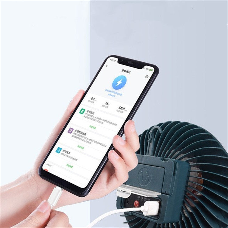 USB fan lamp with dark housing and circular power control, used with smartphone