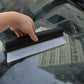 Handheld I-shaped water scraper wiping condensation from car windshield