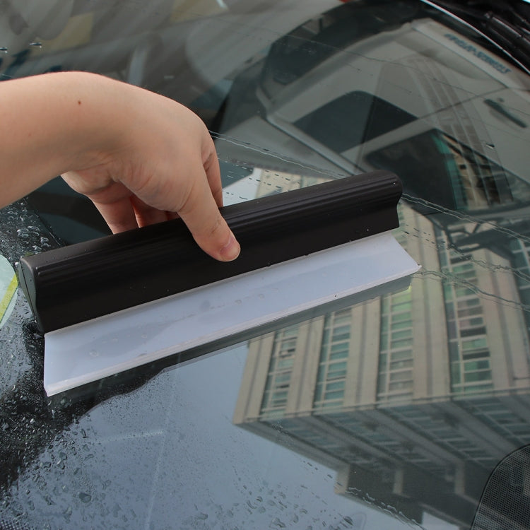 Handheld I-shaped water scraper wiping condensation from car windshield