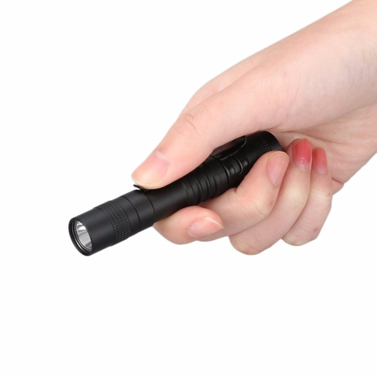Black penlight LED flashlight held in hand with textured grip
