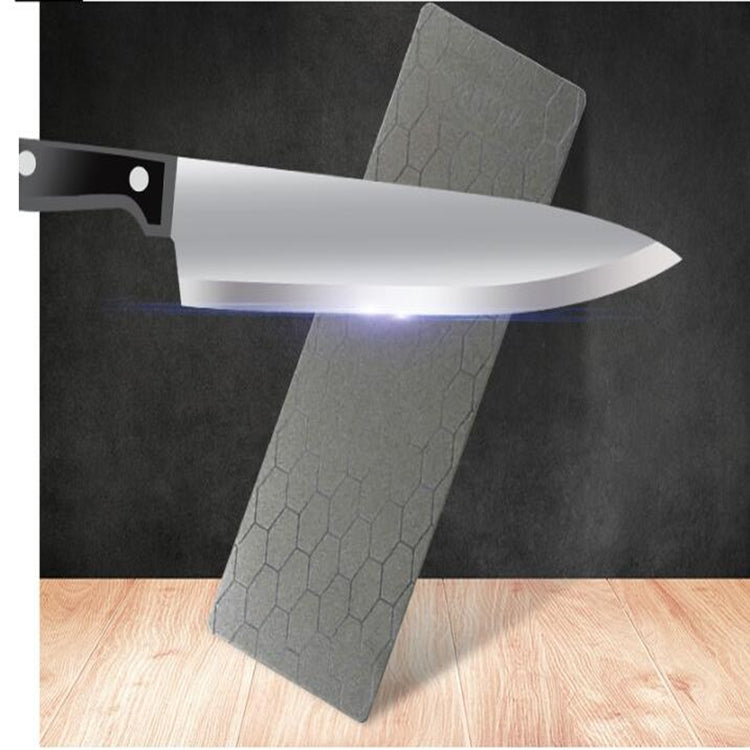 Square knife sharpener whetstone stone with textured gray surface, knife blade resting on it