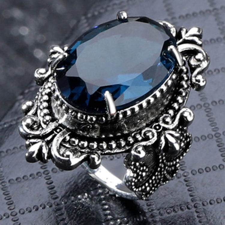 Silver-tone ring with large dark-blue faceted oval gemstone, detailed claw setting