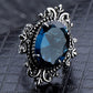 Vintage silver ring with oval blue gemstone and raised scroll filigree bezel