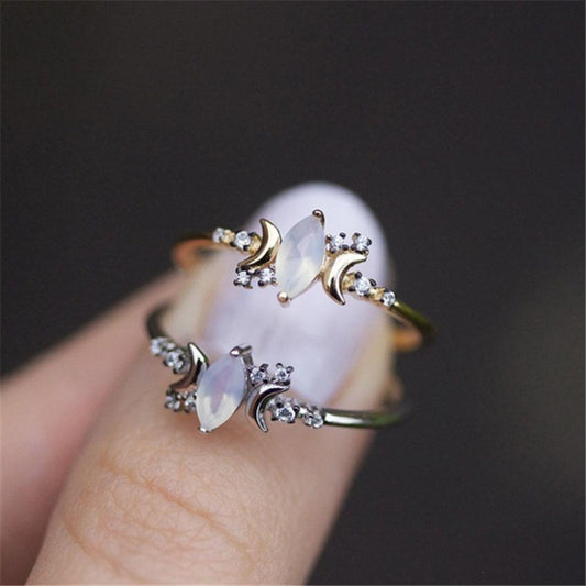 Opal ring with crescent moon and crystal accents, shown in gold and silver tones