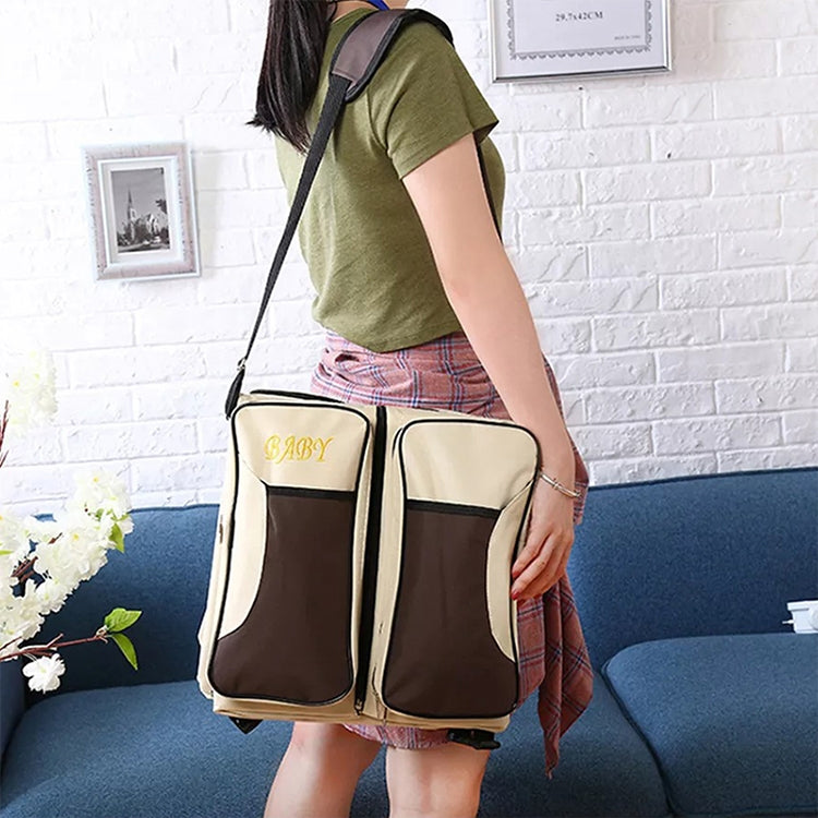 Brown and beige portable baby travel foldable bed bag worn on a shoulder strap