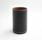 Black faux-leather pen holder organizer, round cup with tan interior and stitched base.