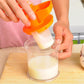 Manual soybean juicer straining pale soy milk in clear glass jug with orange lever