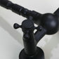 Close-up of black faucet controls with round plate and cross handle levers