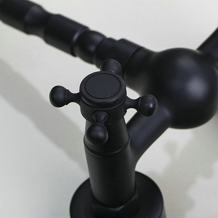 Close-up of black faucet controls with round plate and cross handle levers