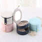Set of round two-tier jewelry storage boxes in white, pink, and blue with hinged lids.
