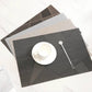 Dark gray table mat with geometric check pattern and a cup set on top.