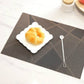 Dark gray geometric check table mat with a white scalloped plate and small spoon.