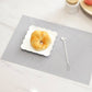 Light gray geometric check table mat with textured surface, with white plate and spoon.