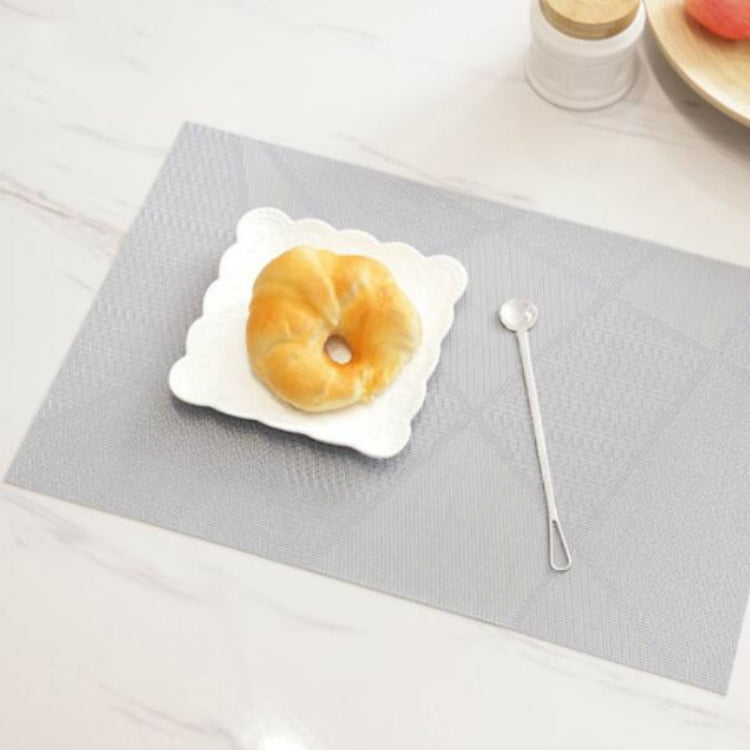 Light gray geometric check table mat with textured surface, with white plate and spoon.