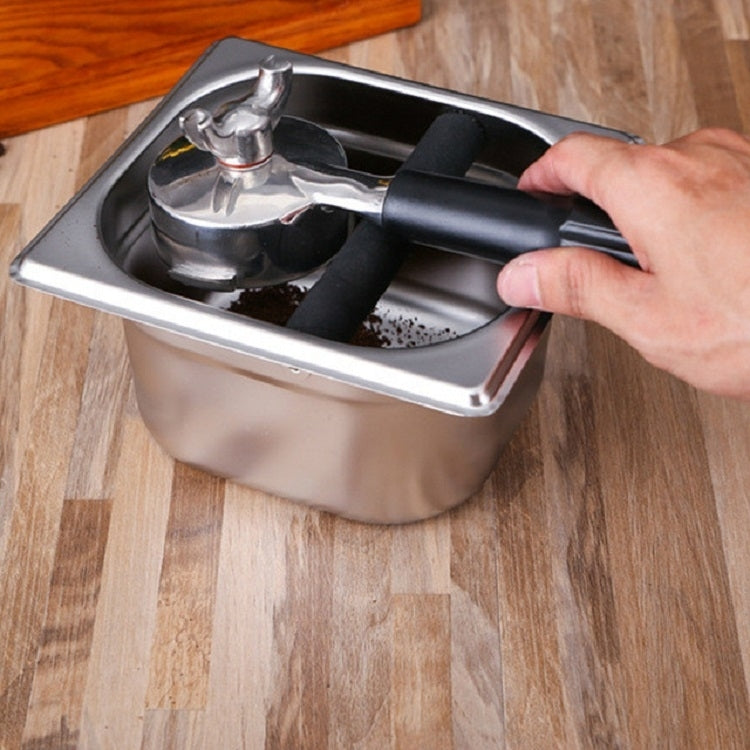 Stainless steel coffee grounds bucket with black scoop handle being used