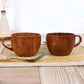 Set of two brown wooden cups with handles, carved wood grain texture
