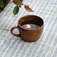 Brown wooden mug with handle, white flower detail near the bottom