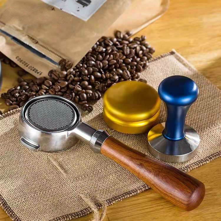 Bottomless filter basket with wooden handle beside blue and yellow tampers