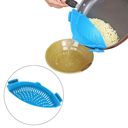 Blue silicone pot filter clip with perforated strainer, draining noodles into a glass bowl