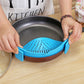 Blue silicone pot filter clip seated on a metal pot rim, hands securing strainer