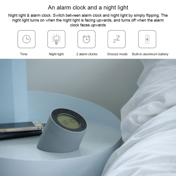 Gray alarm clock night light on a bedside surface with LCD time display facing up.