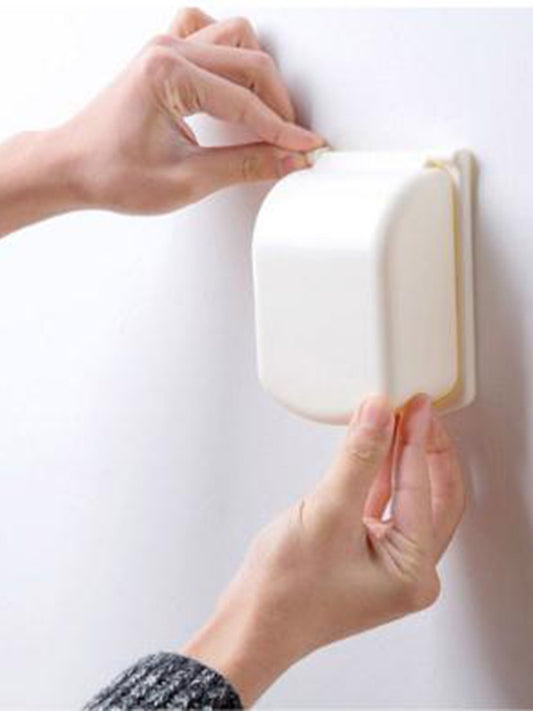 Beige outlet safety cover being fitted by hands over power socket